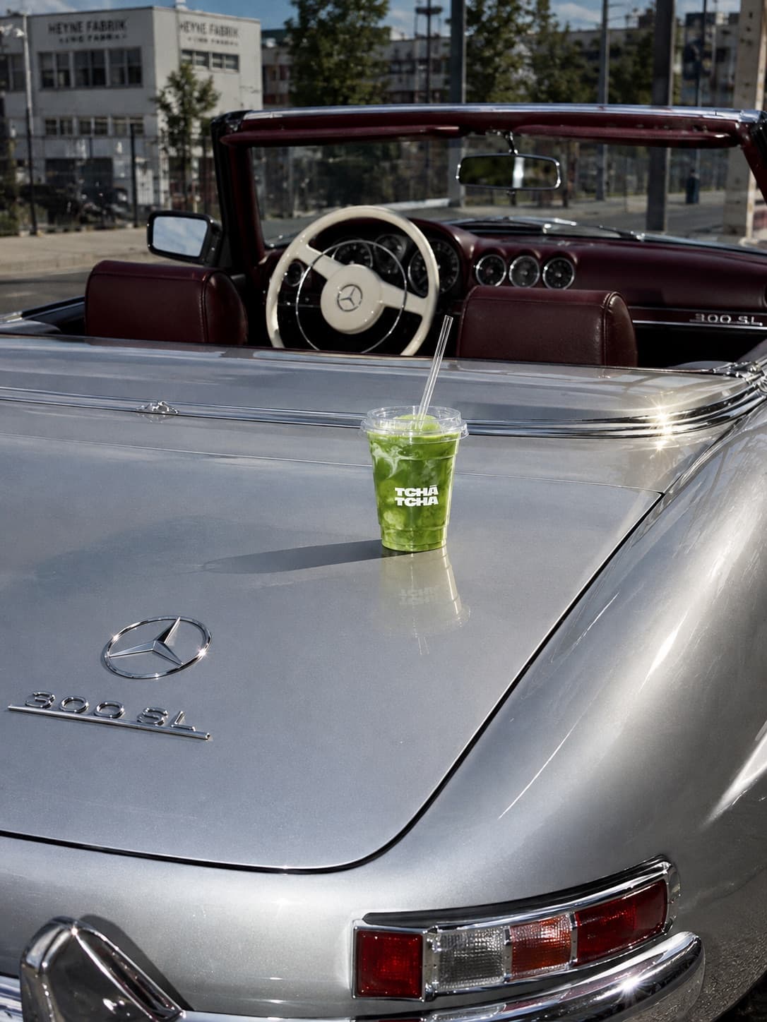 シルバーのメルセデス 300 SL のボンネットに置かれた Tchá Tchá のアイス抹茶