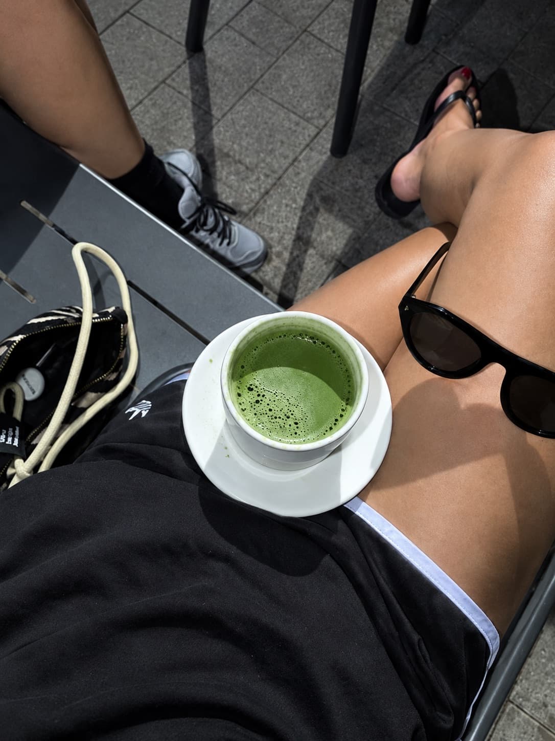 日の当たるテラスで、膝の上に置かれた抹茶のカップ